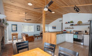 A spacious living area with a fireplace, a dining table, and a kitchen with white cabinets and wooden countertops. - River Retreat with Kayaks, Firepits, Stars (Strasburg)