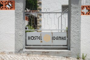 Entrada a un hostal con una reja metálica y un letrero que dice 'HOSTEL IDANHA'.