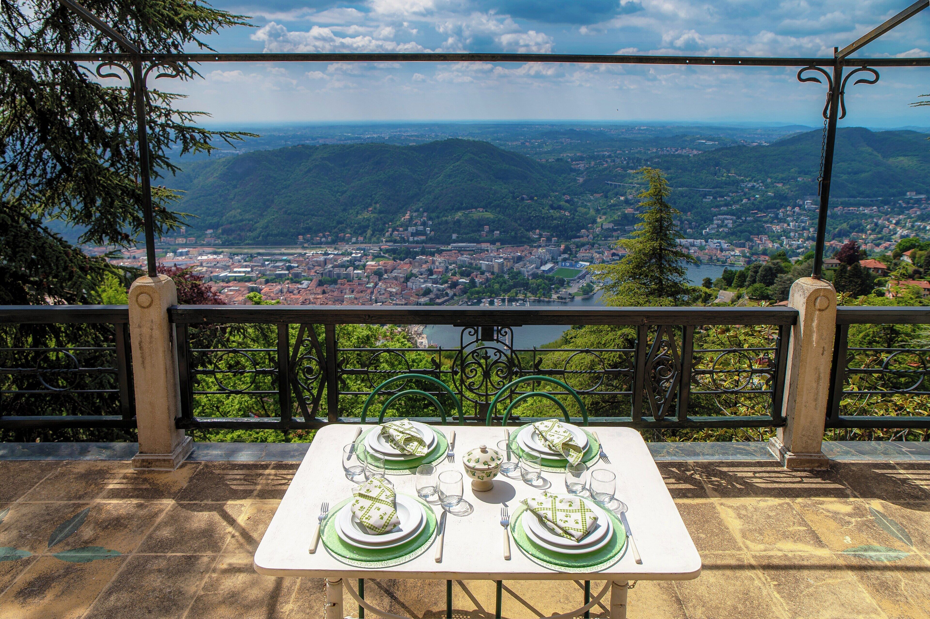 Une table dressée pour quatre personnes, avec une vue panoramique sur une ville et des montagnes en arrière-plan.