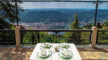 Une table dressée pour quatre personnes, avec une vue panoramique sur une ville et des montagnes en arrière-plan.