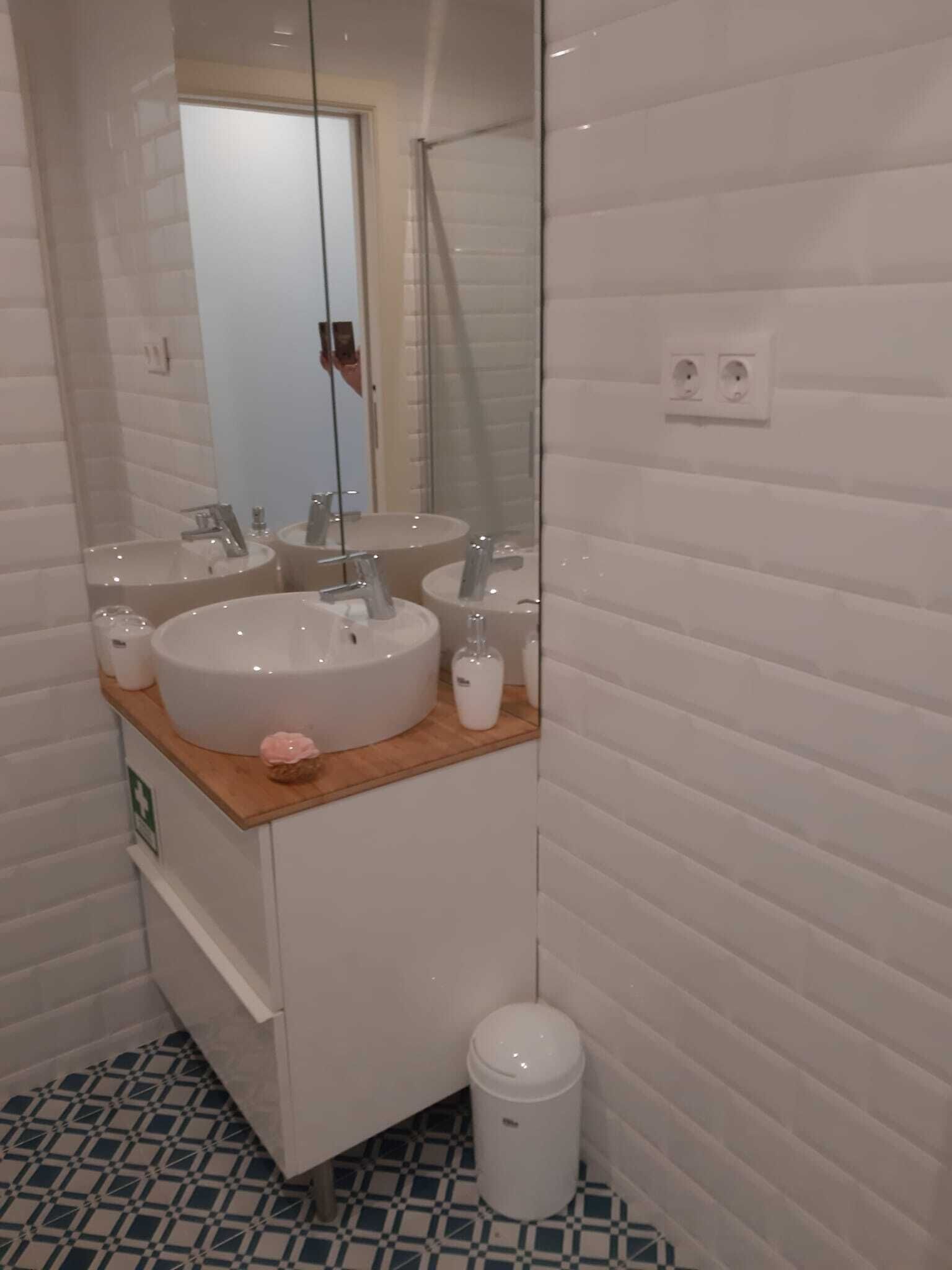 Un baño moderno con dos lavamanos redondos, un espejo y un cubo de basura.