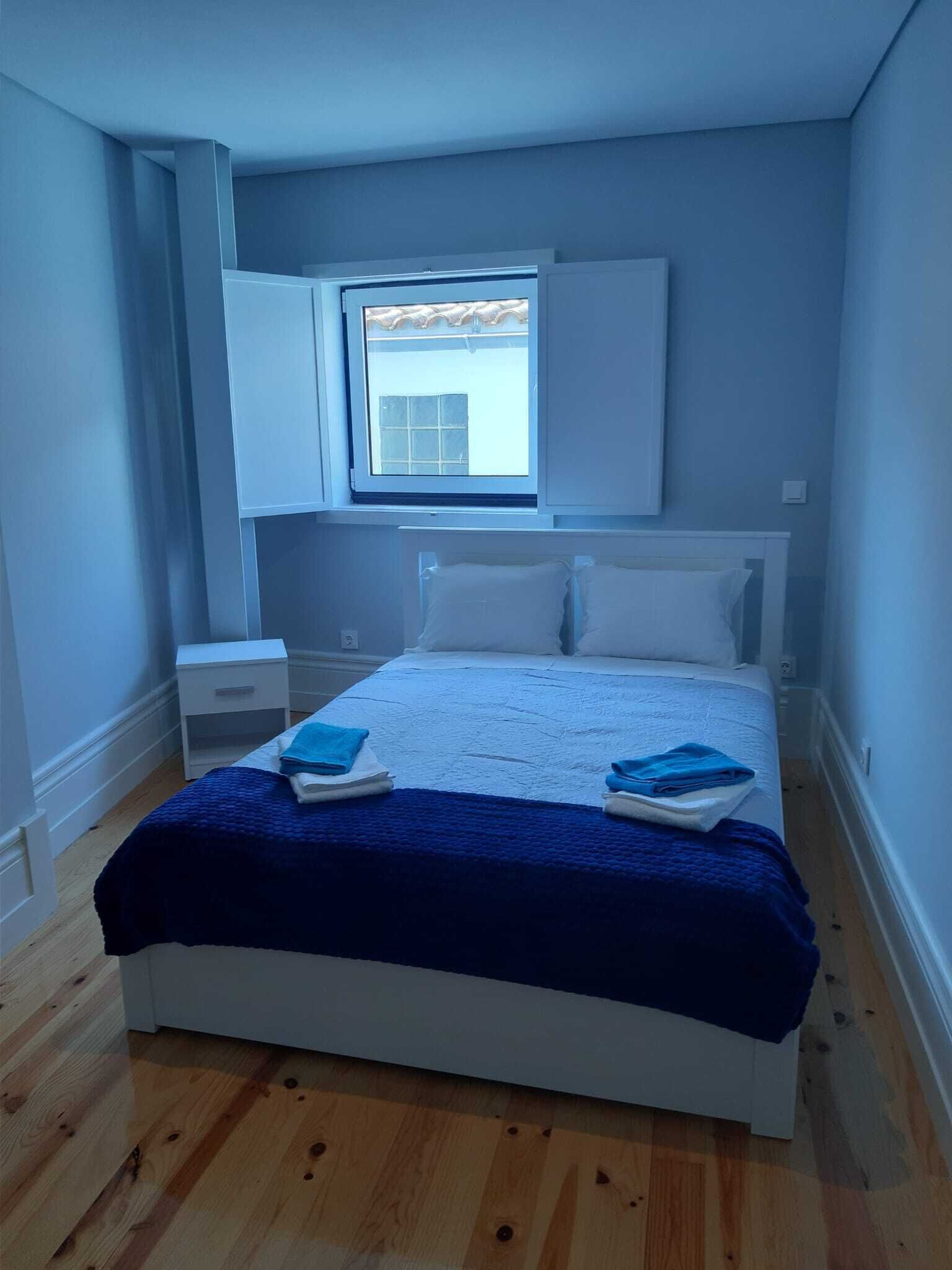 Une chambre à coucher avec un lit, une table de chevet, une fenêtre et une vue sur l’extérieur.