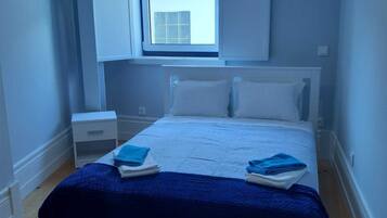 Une chambre à coucher avec un lit, une table de chevet, une fenêtre et une vue sur l’extérieur.