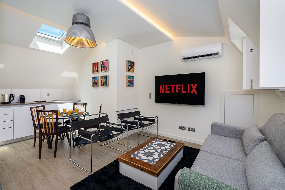 A modern living room with a sofa, a coffee table, and a dining area with a table and chairs.