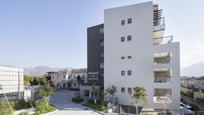 A modern multi-story building with balconies, labeled "ROYAL ON MAIN," surrounded by a parking area and greenery. - Immaculate 2-bed Apartment in Cape Town (Cape Town)