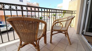 Two wicker chairs on a balcony with a view of a street and buildings in the background. - Samiras Home Cozy Apartment Near the Beach and Otrantos Historic Center (Otranto)