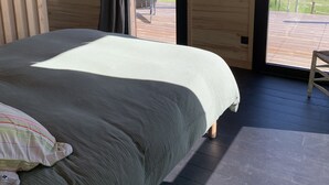 A bedroom with a bed, a window, and a view of a grassy area. - Séchoir à Tabac Contemporain (Aillas)