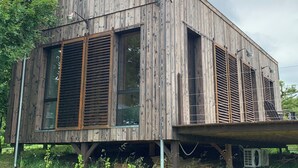 A wooden house with large windows and shutters, a sloped roof, and a balcony. - Séchoir à Tabac Contemporain (Aillas)