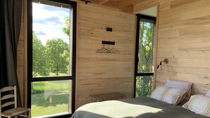 A bedroom with a bed, a chair, and a large window. - Séchoir à Tabac Contemporain (Aillas)