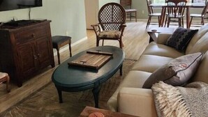 Een woonkamer met een bank, salontafel, televisie en een eethoek met stoelen en een tafel.
