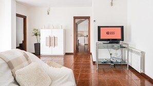 A hotel room with a TV displaying "GUEST READY," a white wardrobe, a glass coffee table, and a cozy sofa. - Relaxing time near the river (Rio Mau)