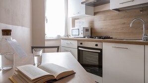 A modern kitchen with a microwave, stove, oven, and a wooden countertop. - Italianway Comfort - Campania 26 A (Milan)
