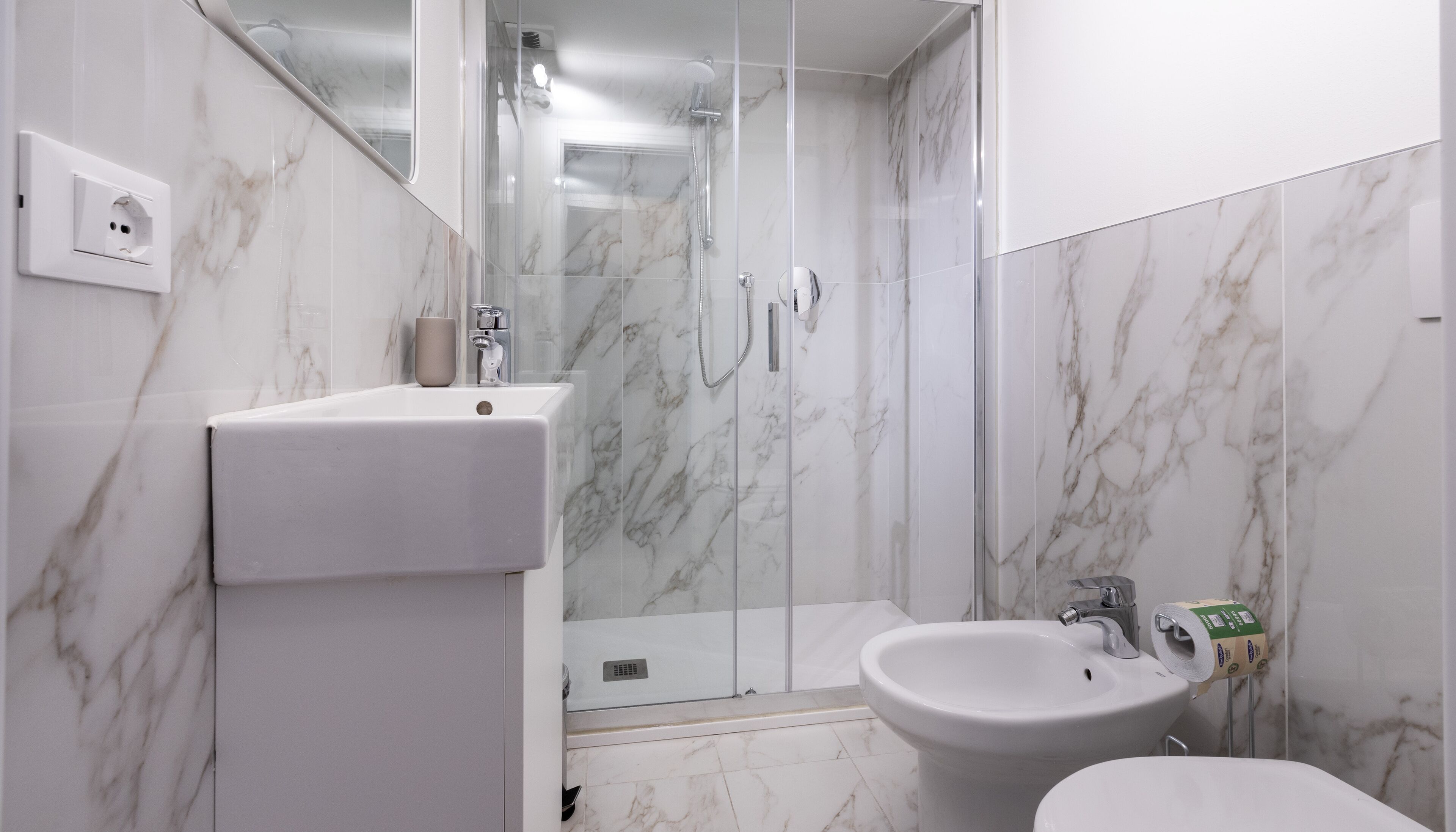 A bathroom with a shower, sink, and bidet.