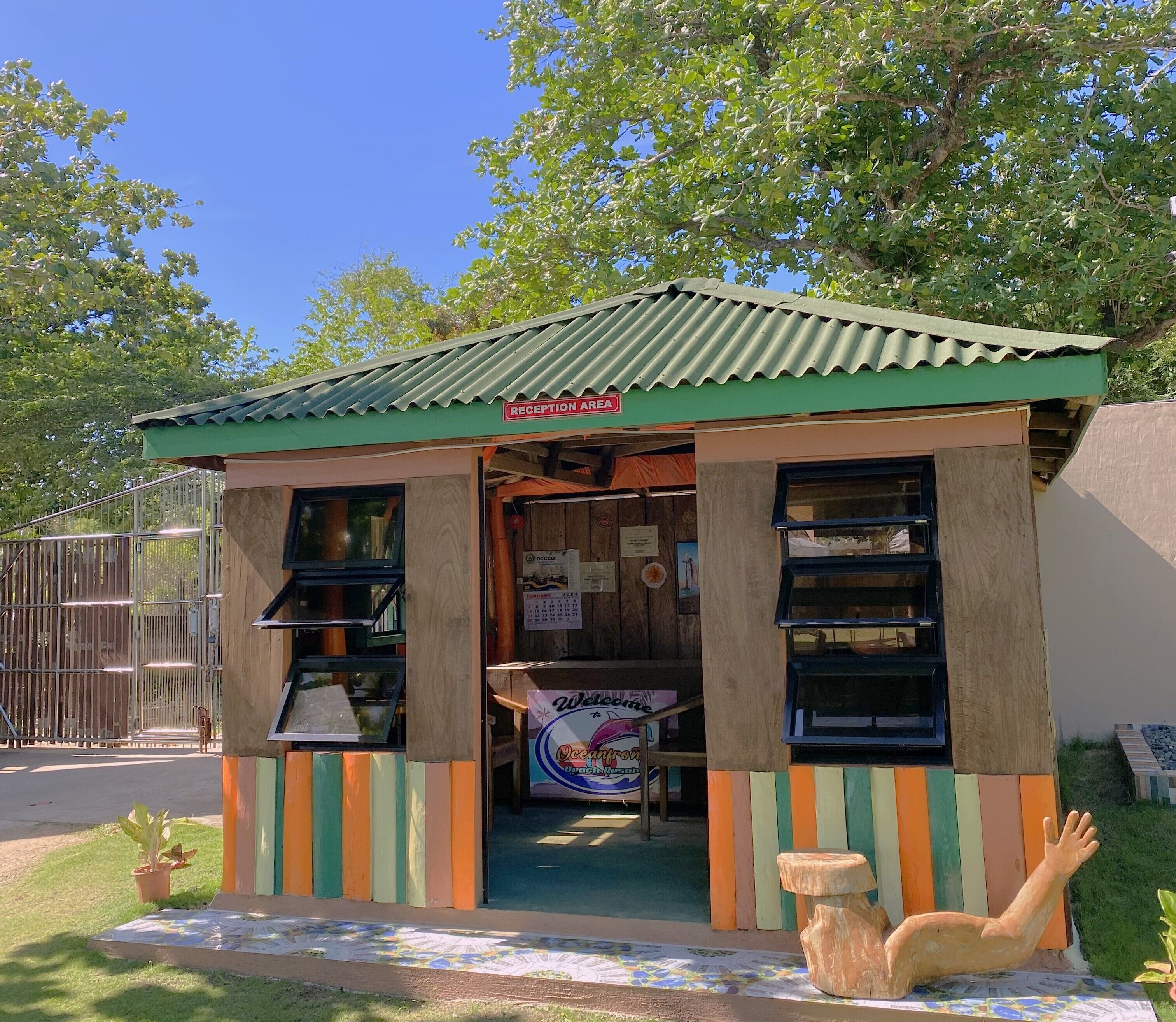 A small, colorful reception area with a corrugated metal roof and a sign indicating it's the reception area.
