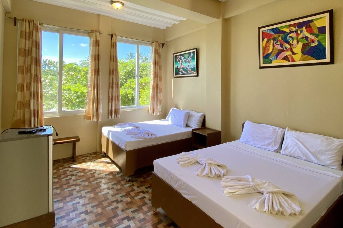 A hotel room with two beds, a desk, and a window with curtains.