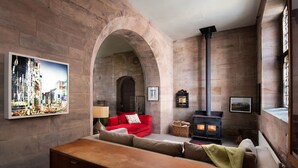 Una sala de estar acogedora con chimenea de piedra, un sofá rojo y una mesa de centro de madera.