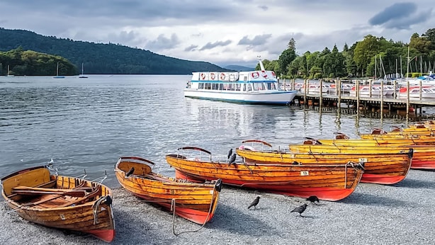 Un lago con barcos amarrados en un muelle, rodeado de árboles y colinas.