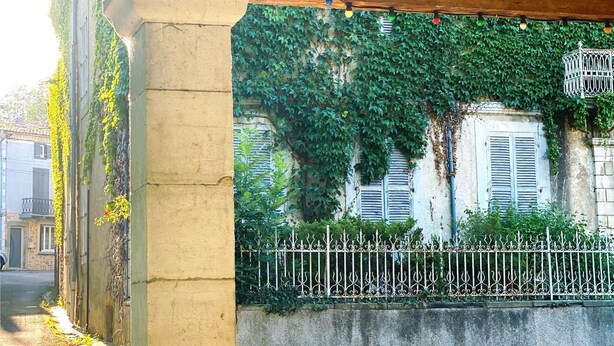 Un’area esterna riparata con un pilastro in pietra, una recinzione in metallo e una panchina.