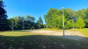 Un espacio al aire libre en un parque con equipamiento para ejercicios, árboles y farolas.