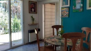 Un comedor con mesa de vidrio, sillas de madera y una pared de acento color turquesa.