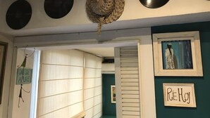 Una habitación con una pared decorada con discos de vinilo, un cuadro enmarcado y un cartel que dice "RIE HOY".