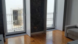 Un salon spacieux doté d’un parquet, d’un canapé gris et d’une table.