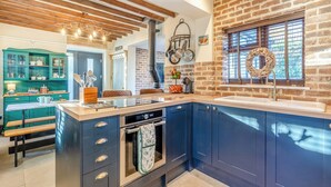 Una cocina moderna con armarios azul oscuro, una isla central y una pared de ladrillo.
