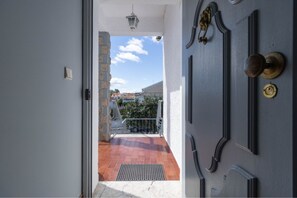 Een deur die uitkomt op een balkon met uitzicht op gebouwen en een heldere lucht.