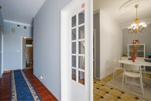 Een gang met een blauw tapijt, een witte deur en een eetgedeelte met een witte tafel en stoelen.