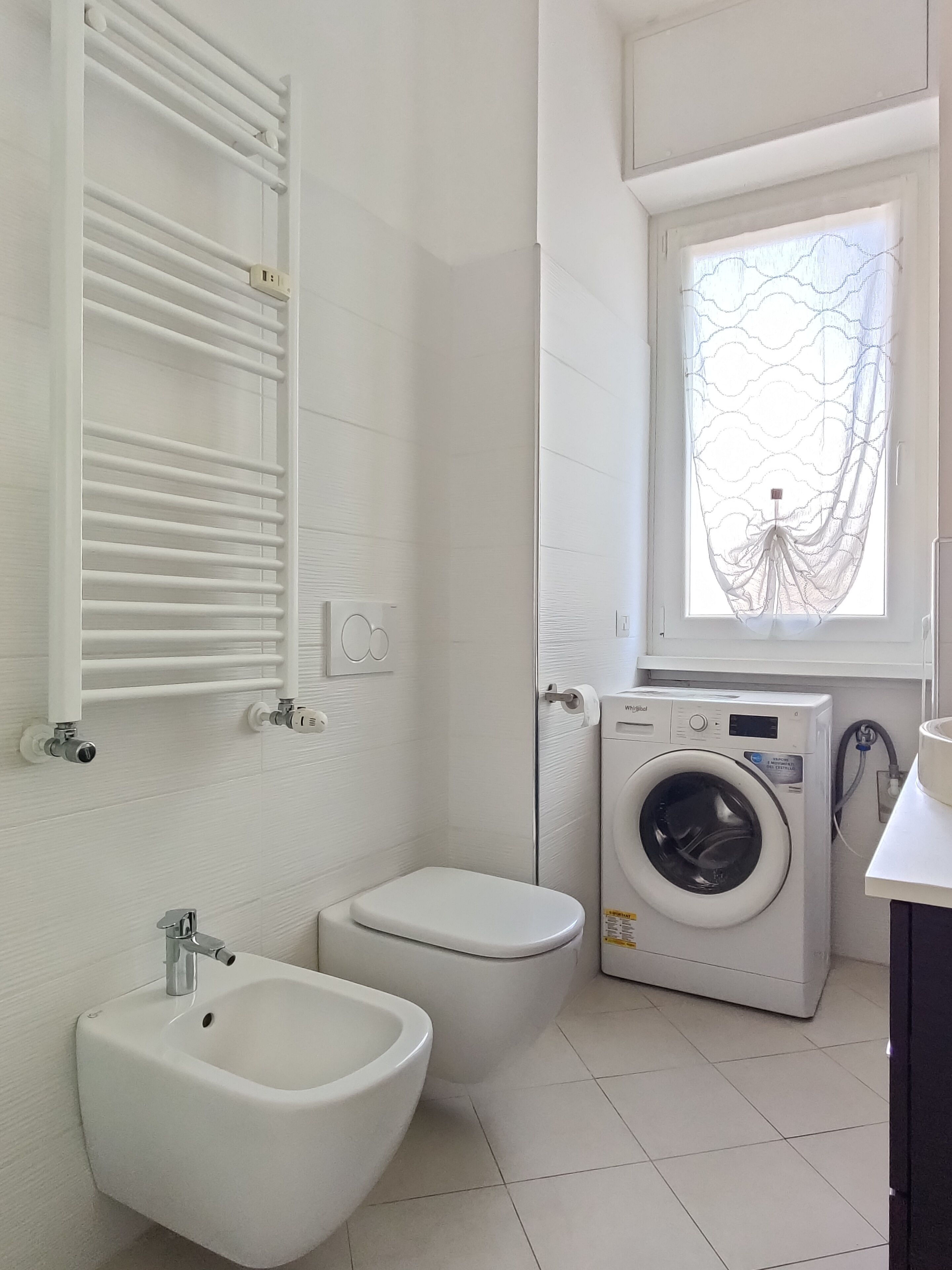 A small, white bathroom with a toilet, bidet, and washing machine.