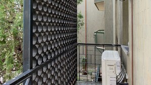 A narrow outdoor corridor with a patterned wall, a metal railing, and a utility box. - Modern Flat - via Crimea 25 (Milan)