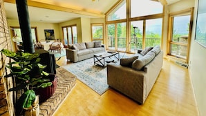 A spacious living room with a fireplace, large windows, and a high ceiling fan. - Fall Color Specials, near Apple Orchards, with Lake & Island Views (Bayfield)