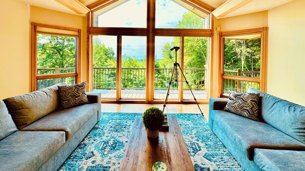 A spacious living room with a high ceiling, large windows, and a balcony with a tripod. - Fall Color Specials, near Apple Orchards, with Lake & Island Views (Bayfield)