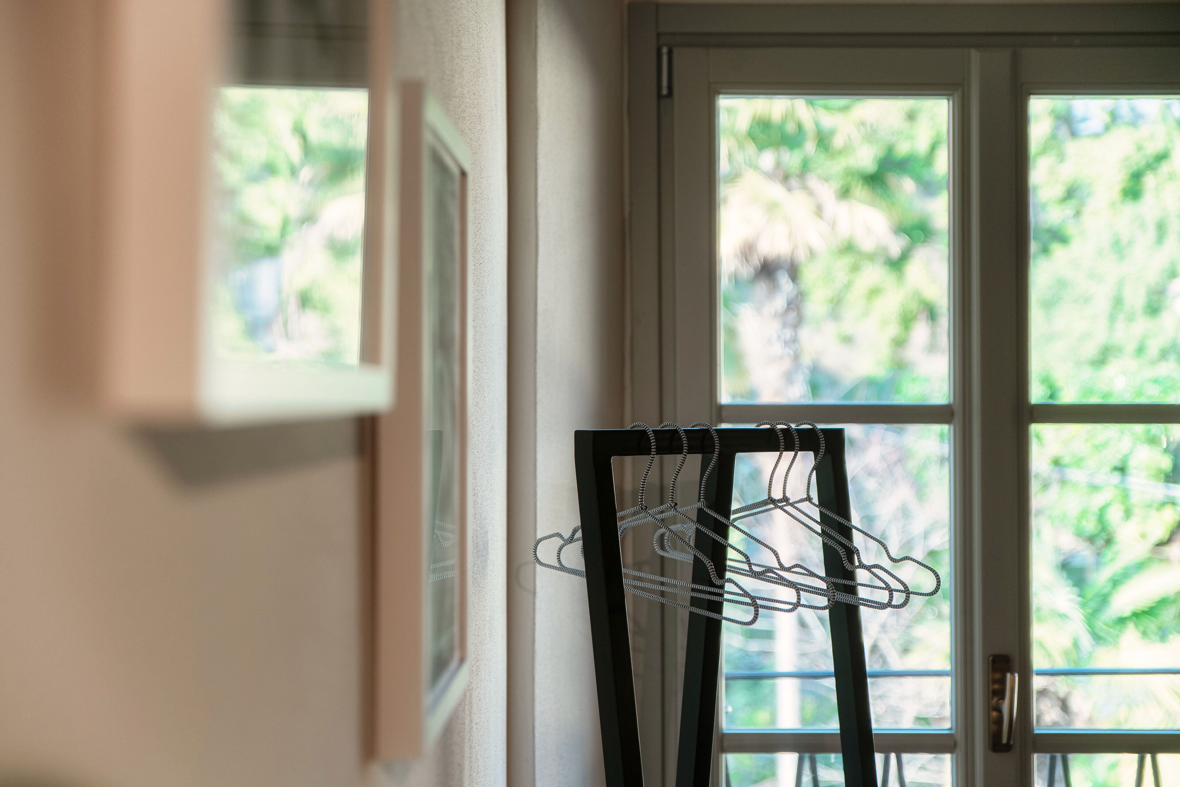 A room with a door leading to a balcony, a coat rack, and framed pictures on the wall.