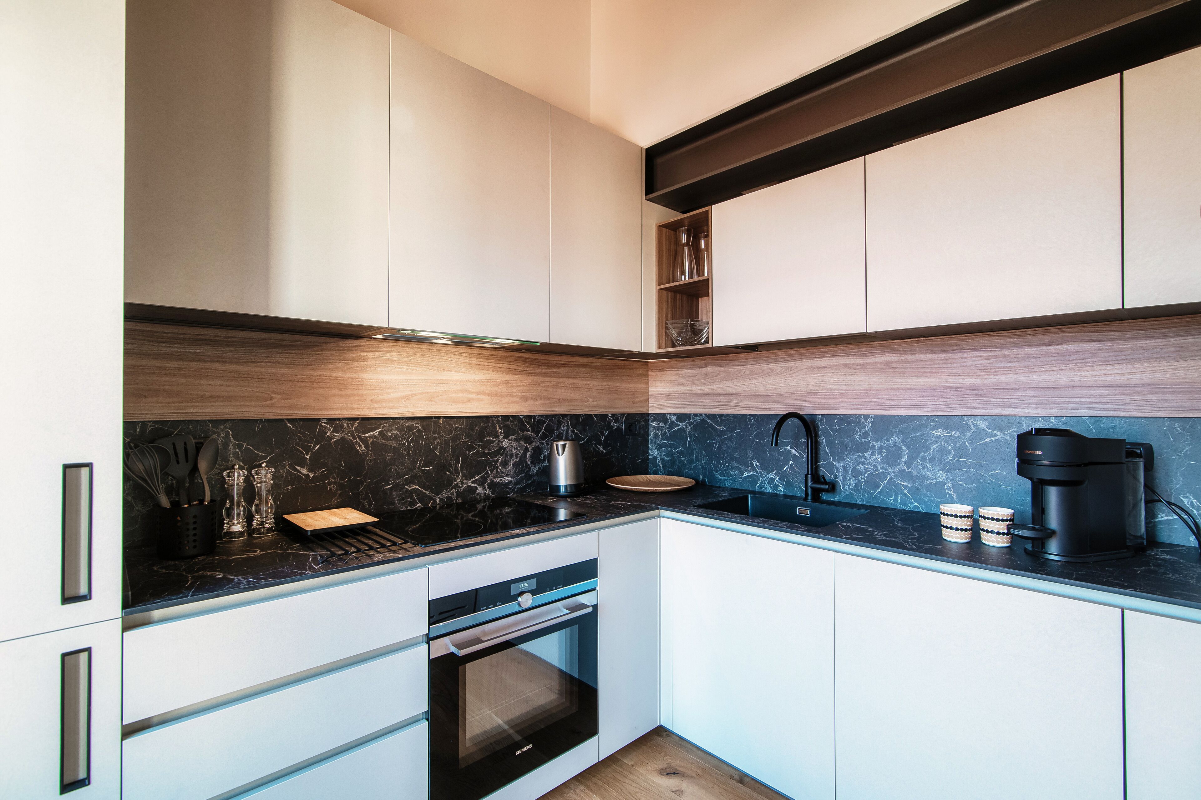 Eine moderne Küche mit weißen Schränken, einer schwarzen Arbeitsplatte und einem eingebauten Backofen.