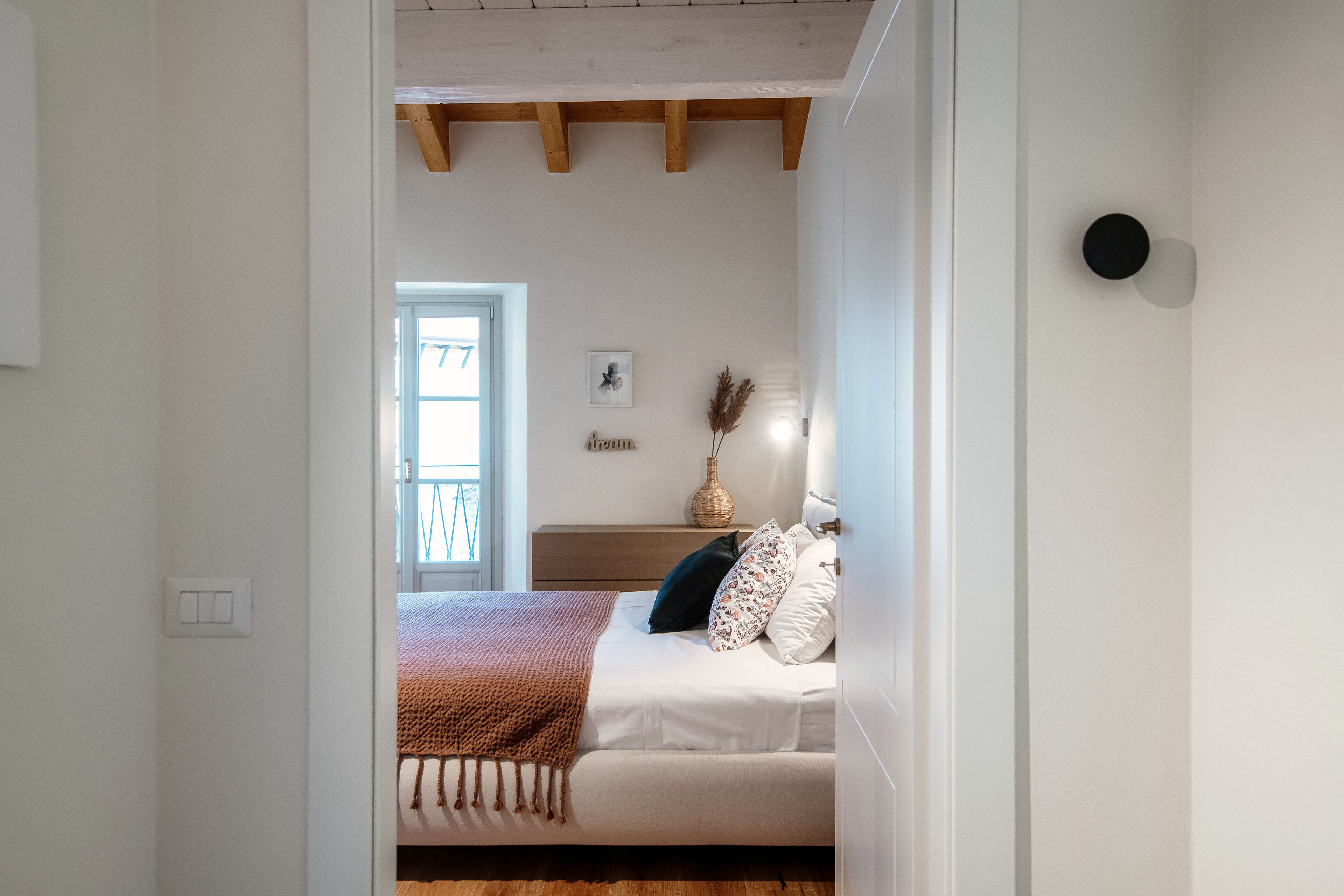 A bedroom with a bed, bedside table, and a wall-mounted lamp.