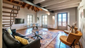Un vaste espace de vie comprenant un escalier, un canapé en cuir noir, une table basse en verre et une table à manger avec des chaises.