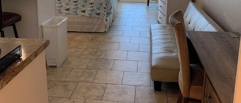 Un dormitorio con cama, escritorio, silla, cómoda, ventilador de techo y balcón con vistas.