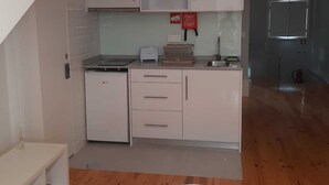 A compact kitchen with white cabinets, a small refrigerator, and a toaster.