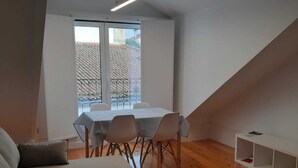 A modern loft-style room with a dining area, a sofa, and a wooden floor.