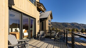 A wooden deck with outdoor seating and a view of mountains.