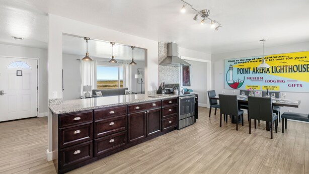 A modern kitchen with a large island, dark cabinetry, and pendant lighting. - Point Arena Lighthouse - Assistant Keeper's House 4 (Point Arena)