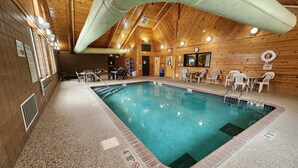 An indoor swimming pool with a wooden ceiling, tiled floor, and multiple seating areas. - Pine Peaks Lodge & Suites (Crosslake)