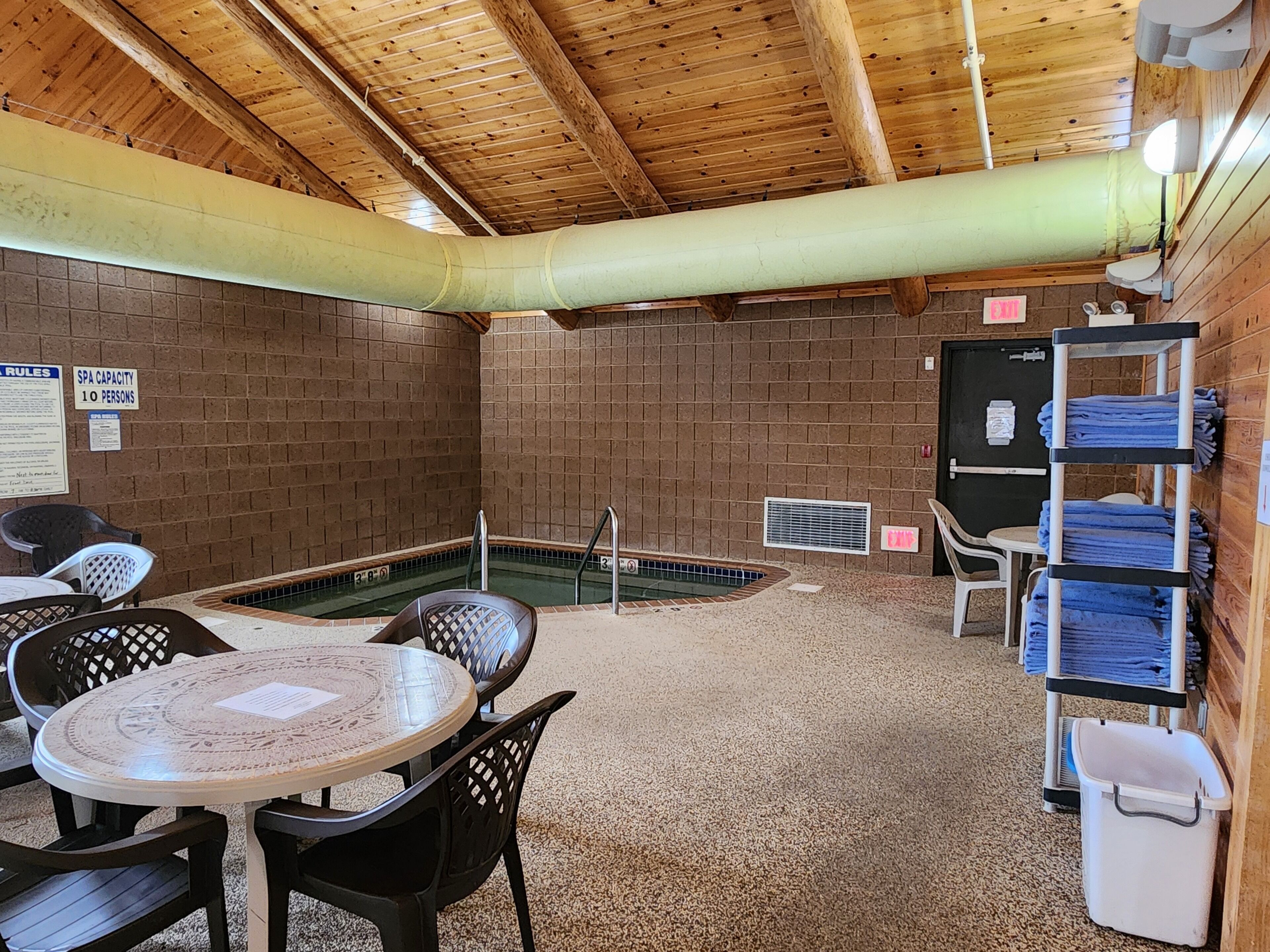 A spa with a pool, seating area, and towel racks.