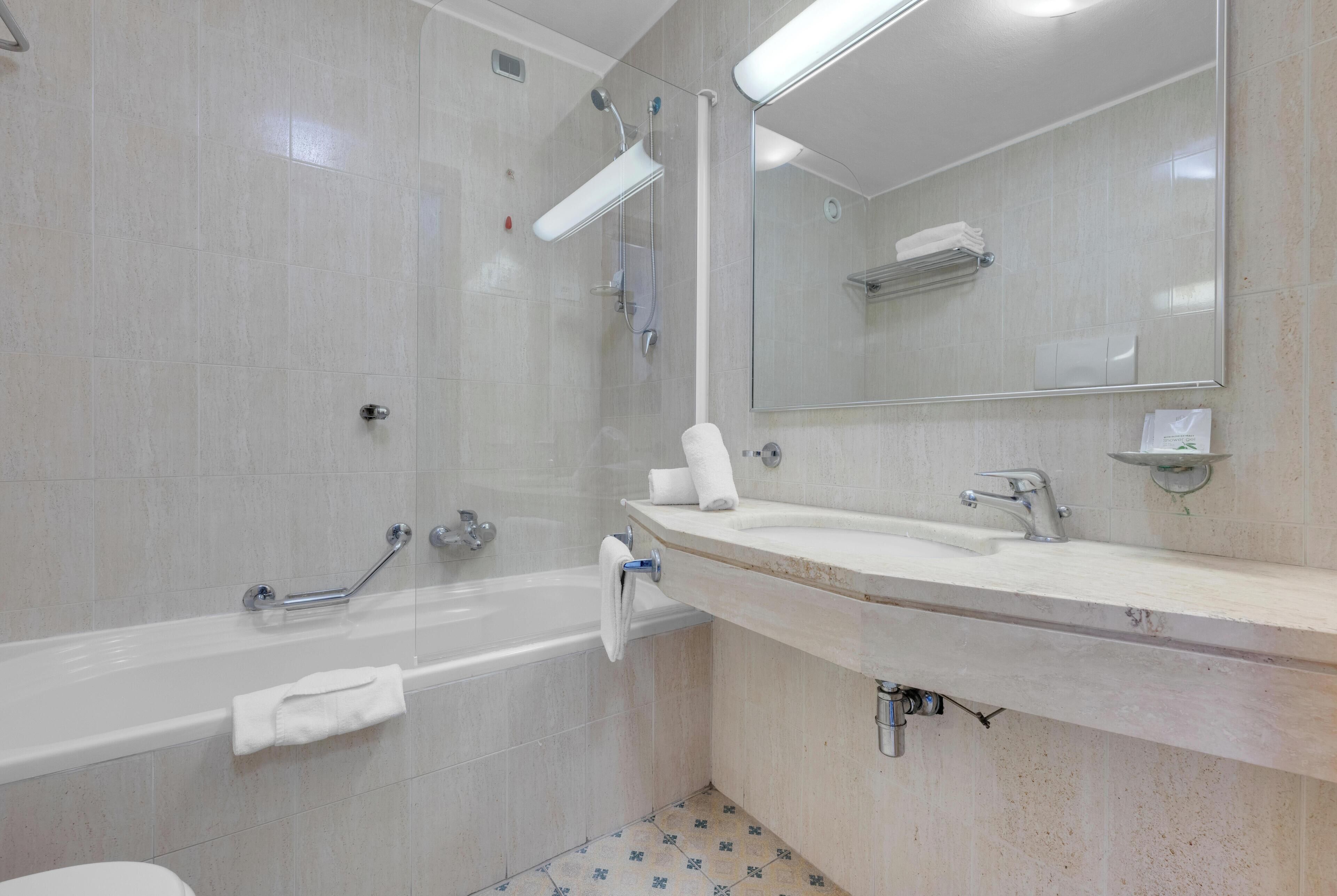 A modern bathroom with a bathtub, a shower, a sink, and a large mirror.