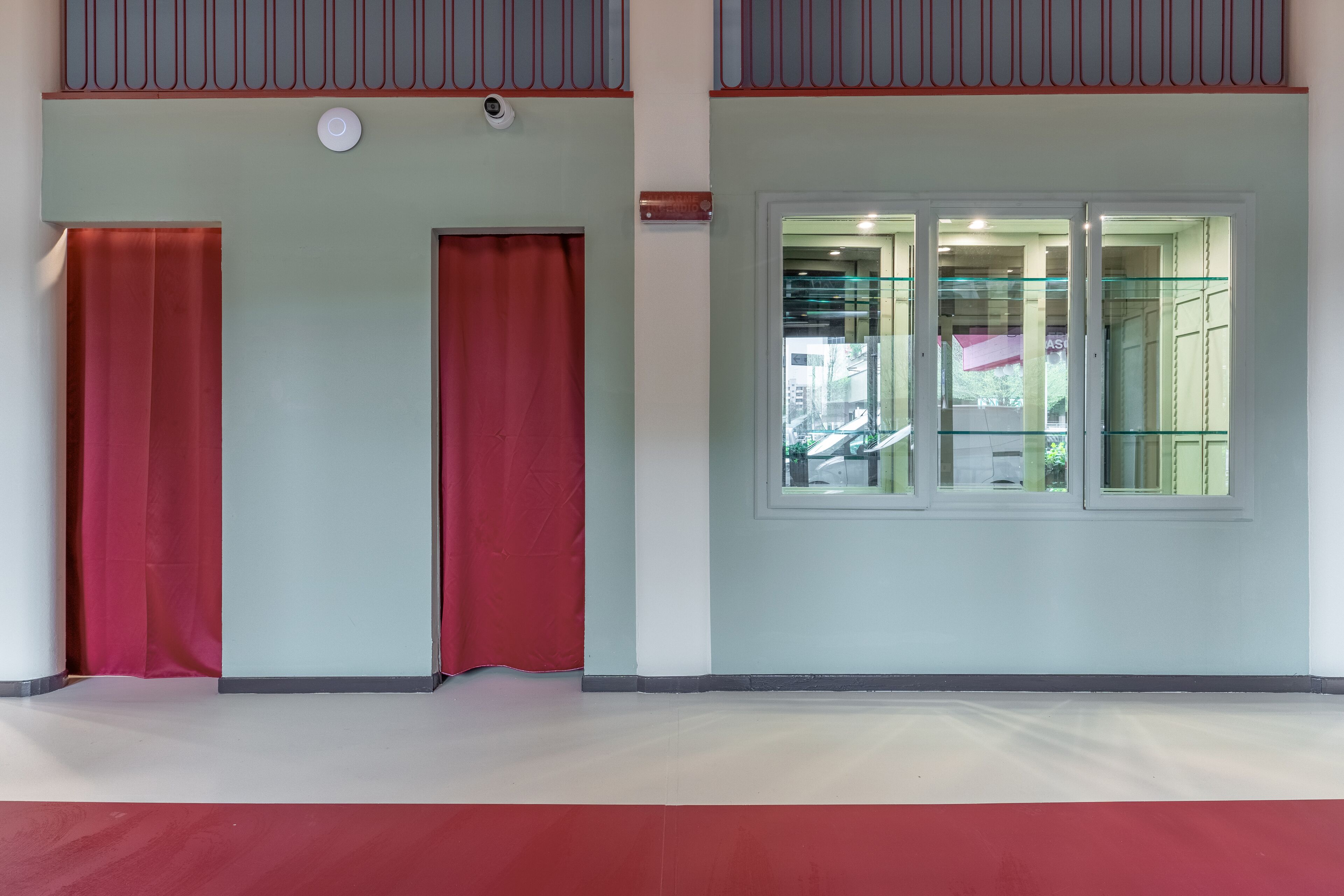 A room with a large window, a door, and a red curtain.