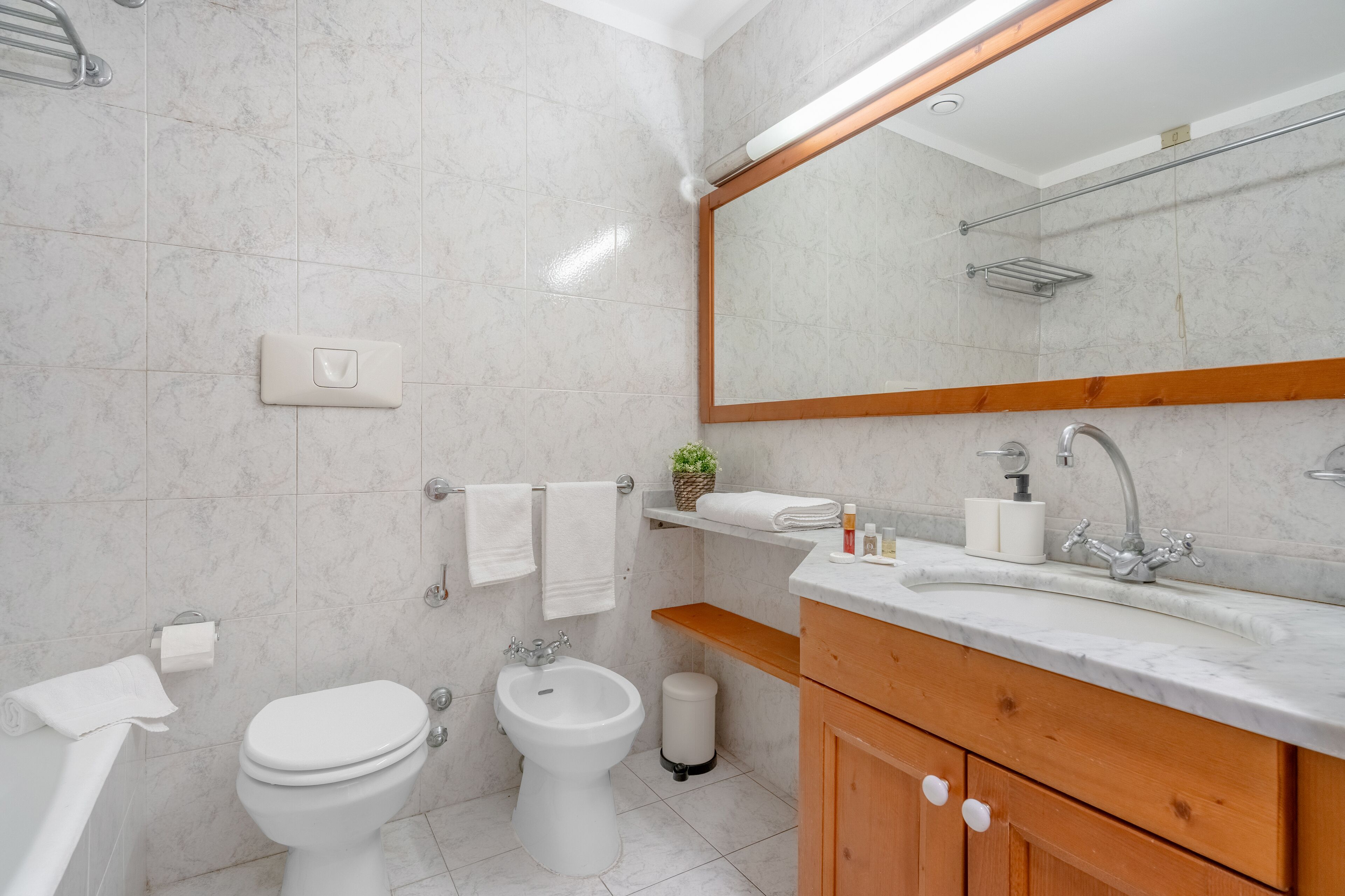 Une salle de bain moderne équipée de toilettes, d’un bidet, d’un lavabo et d’un miroir.
