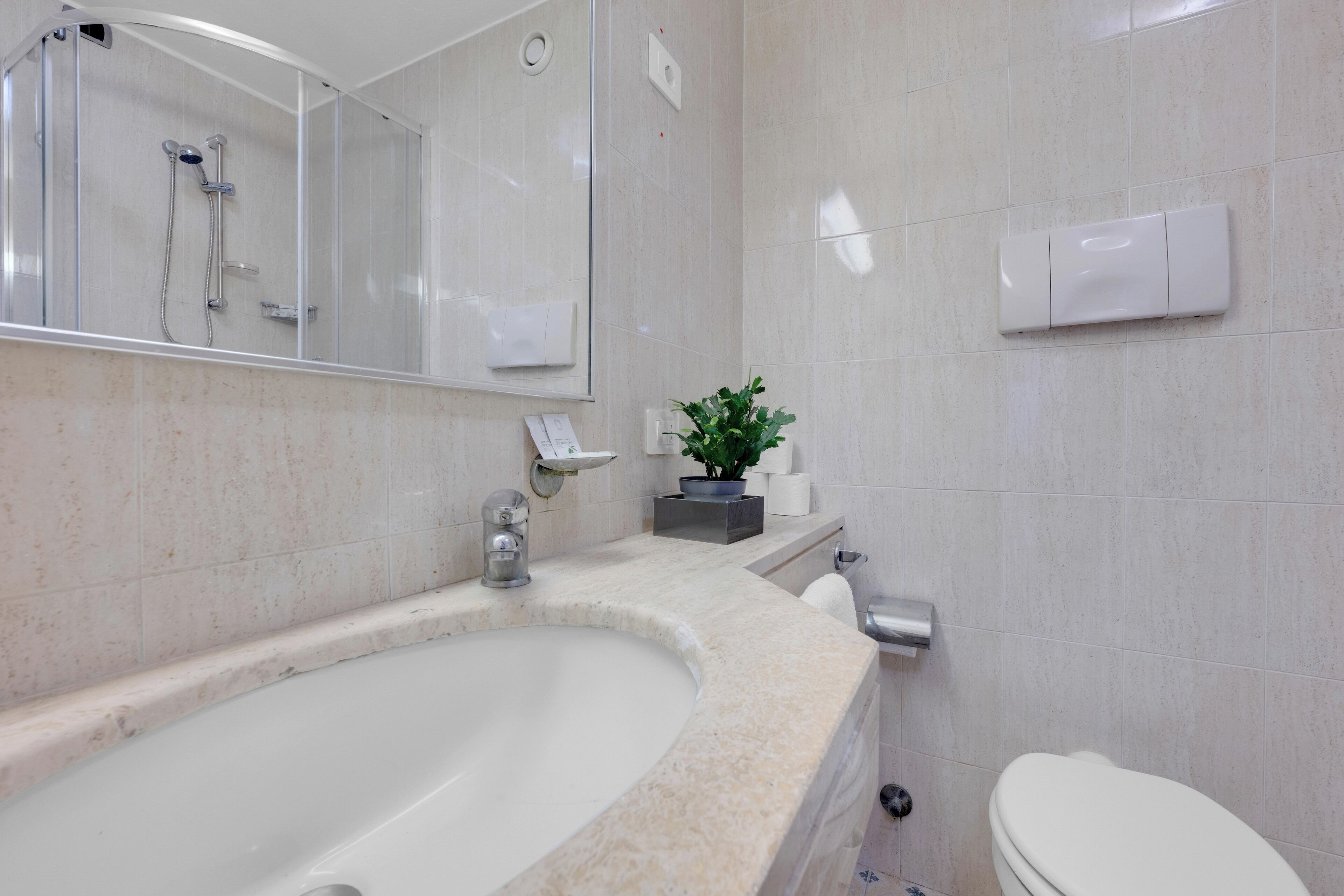 A modern bathroom with a large sink, a mirror, a toilet, and a shower.