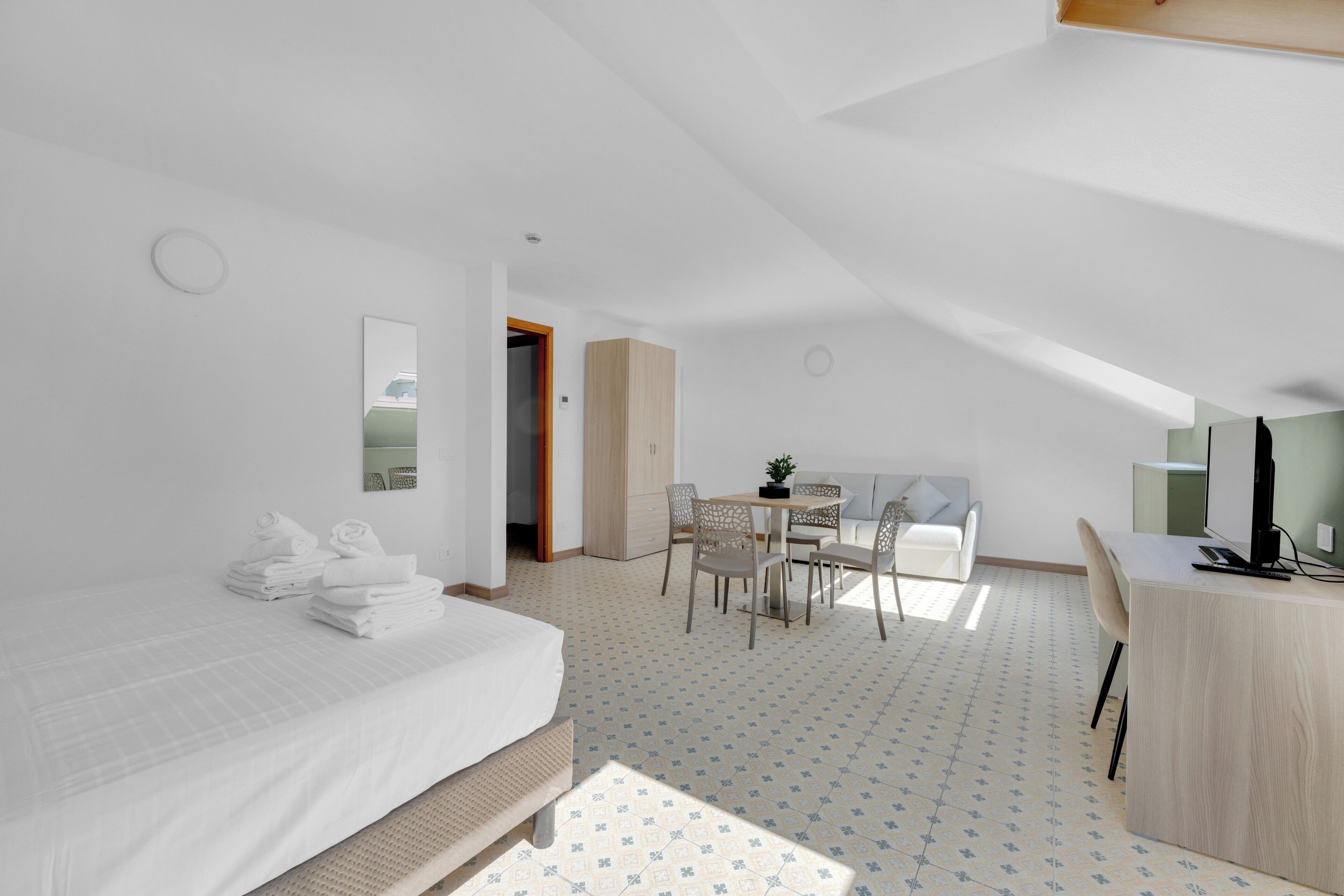 Une chambre moderne et bien éclairée, équipée d’un lit, d’un bureau, d’une chaise et d’un coin repas.