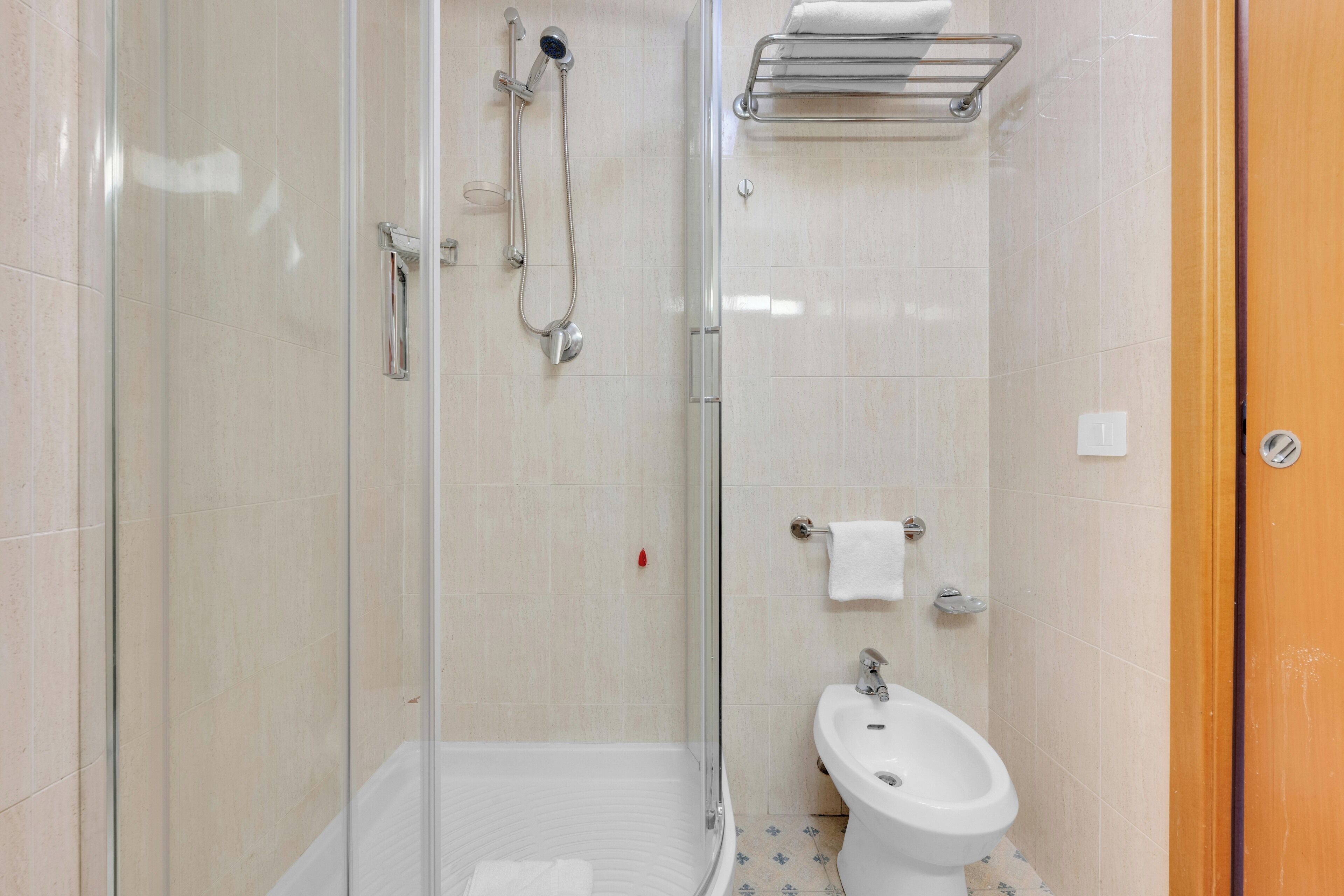 Une salle de bain moderne avec une douche à parois de verre, un lavabo sur colonne blanc et un porte-serviettes.